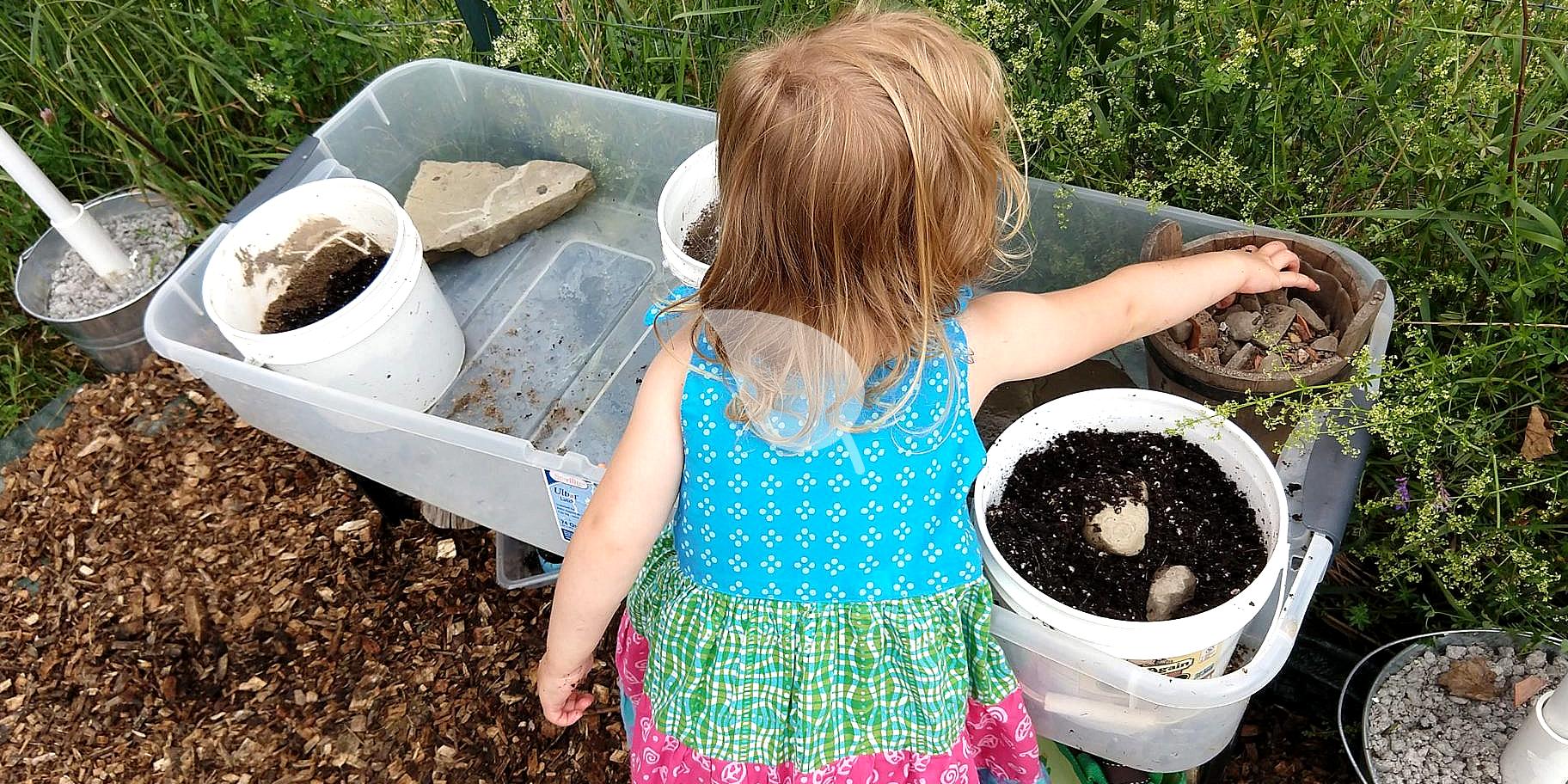 Children playing in a mud garden with tools and buckets
