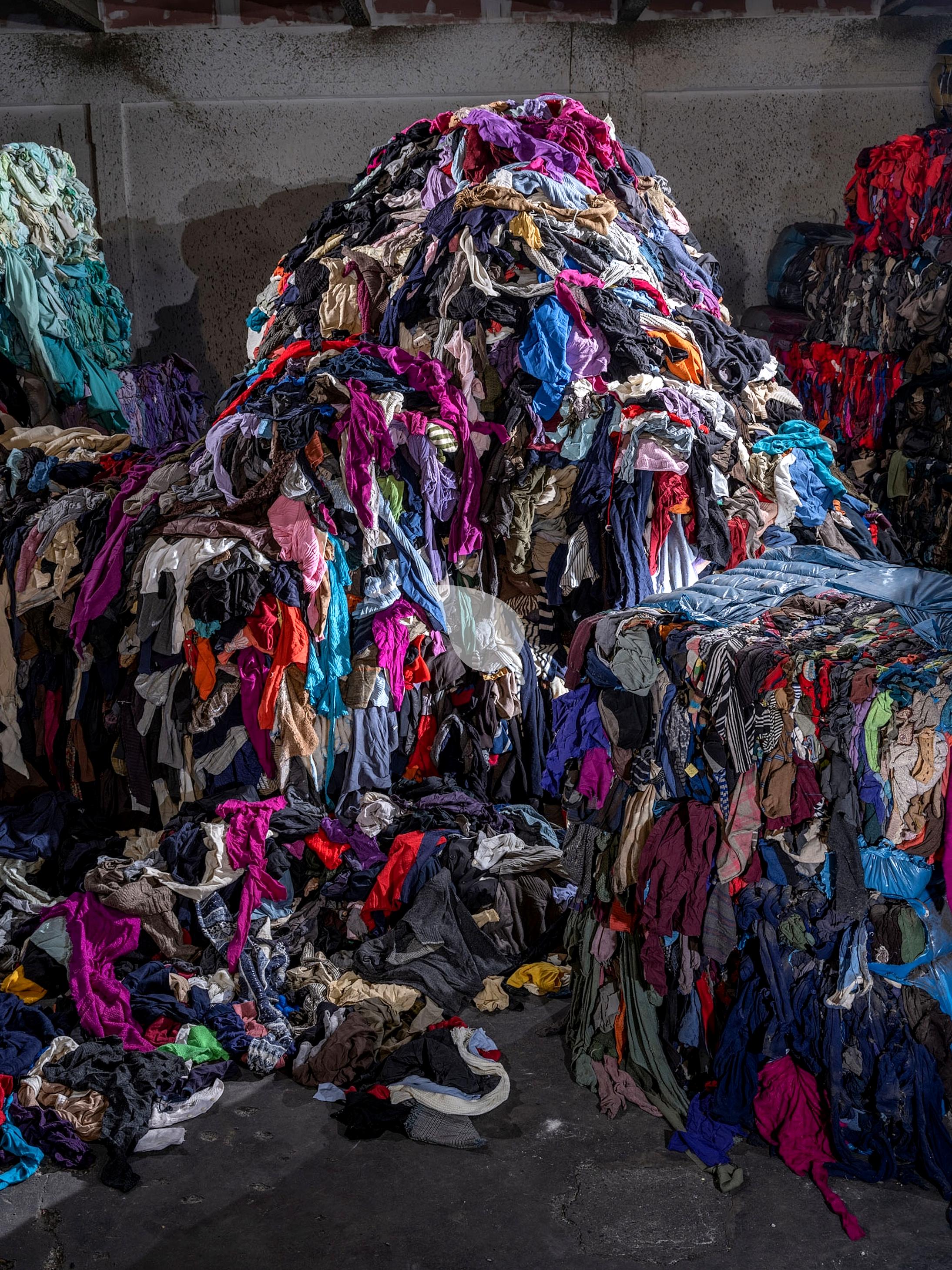 Clothes piling up in landfill illustrating textile waste